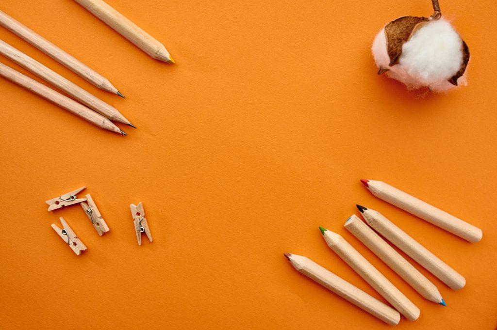 pencils and paper clips on orange background